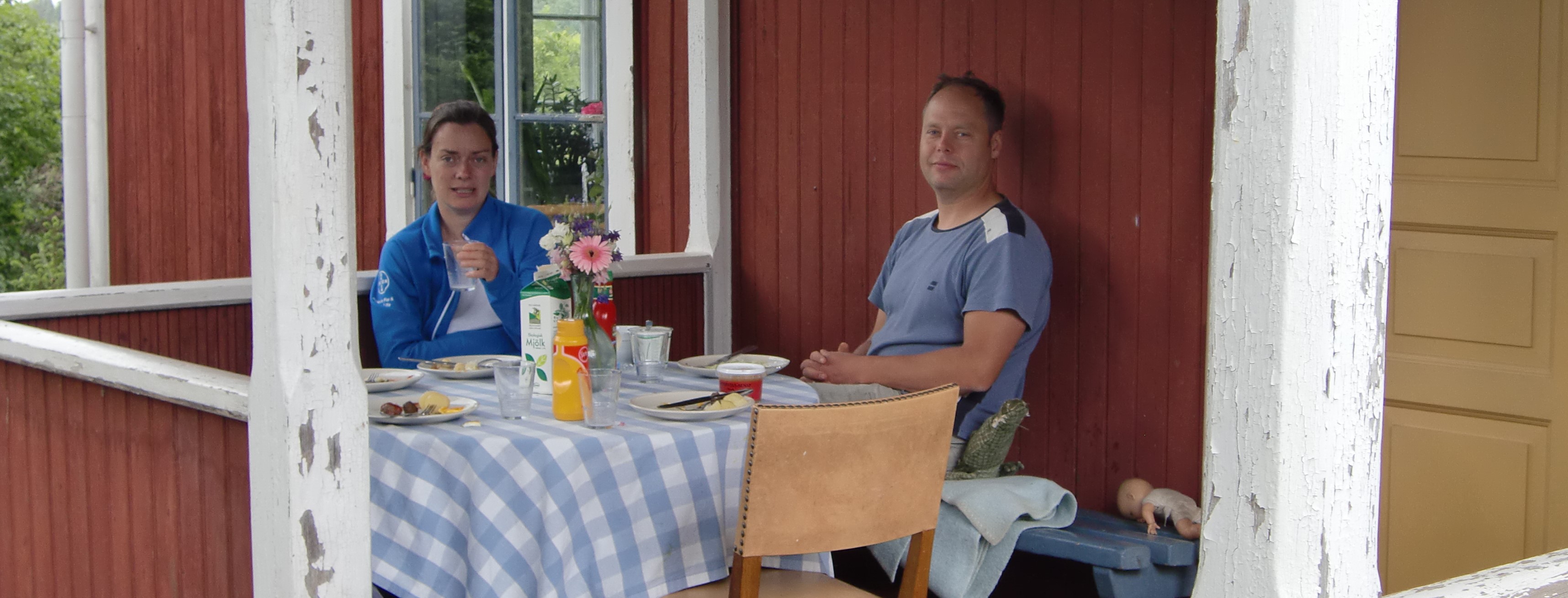 två personer fikar på en veranda