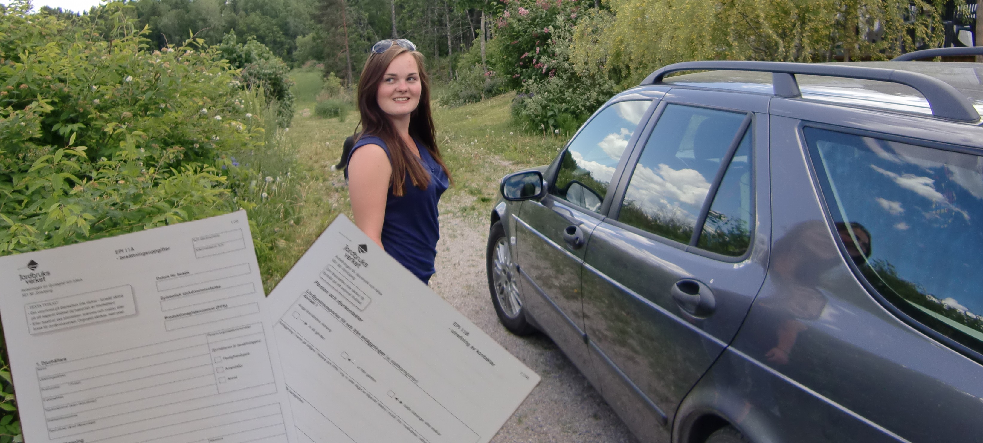 Veterinären står vid bilen och får två blanketter